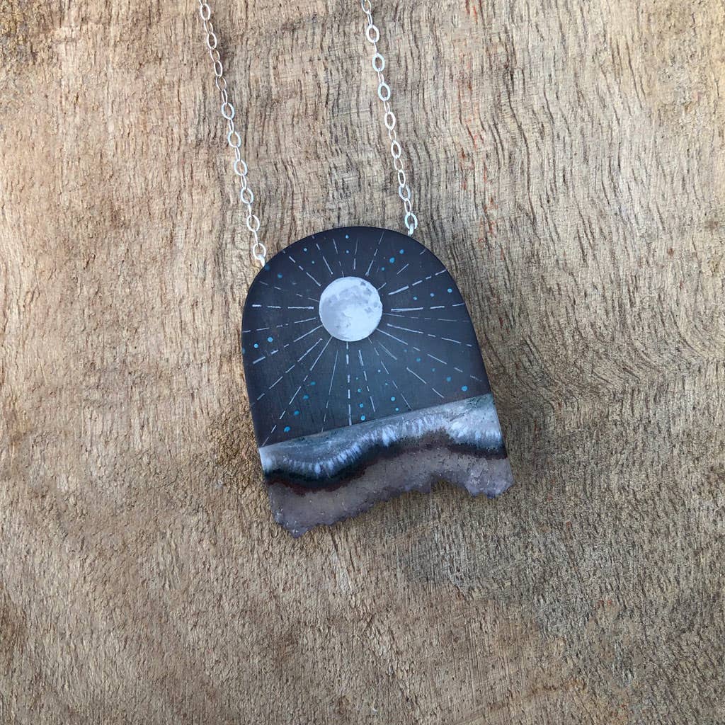 A polished resin crystal necklace with a hand-painted full moon design, attached to a gunmetal chain.