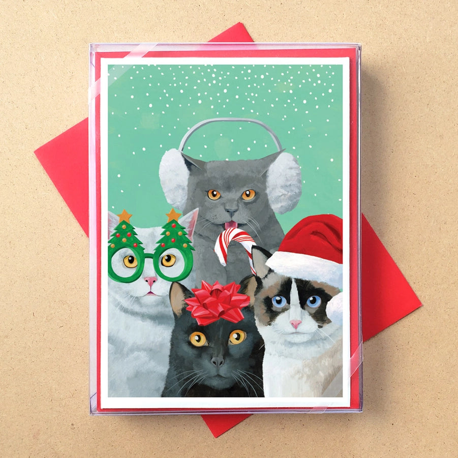 Card with four cats wearing Christmas accessories on a beige background