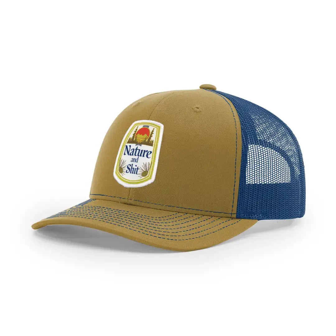 A trucker-style baseball cap with a tan crown and brim, blue mesh back panels, and a rectangular embroidered patch on the front that reads 'Nature and Shit' with a red sun and blue sky graphic.