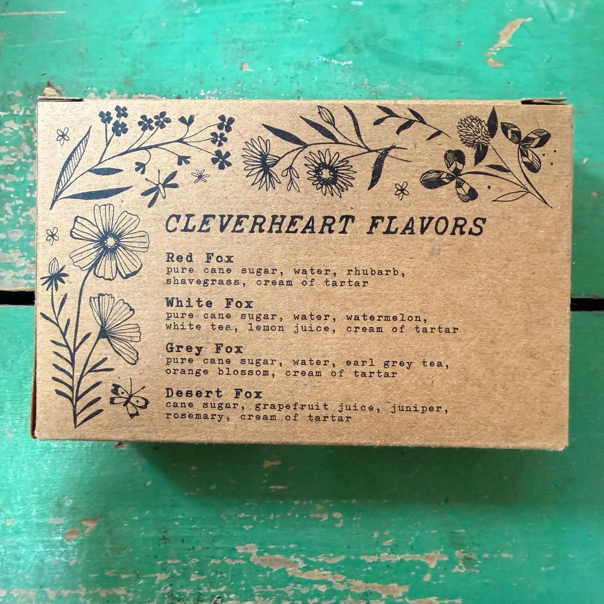 Cardboard box with floral designs and text on a green surface