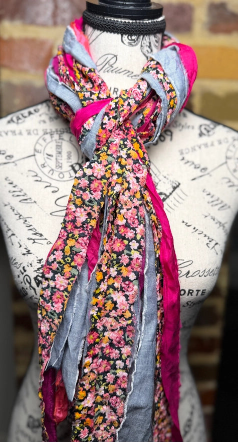 Colorful floral scarf draped over a mannequin head with a decorative background.