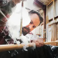 Person holding a large knife with smoke in a traditional setting