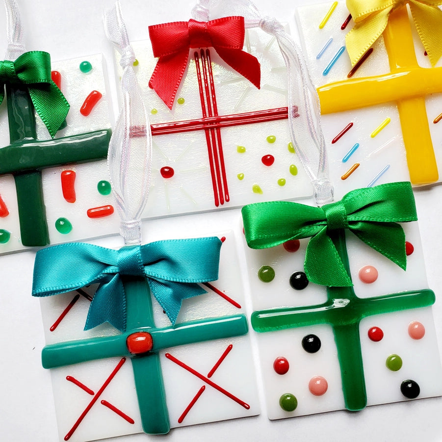 Decorative glass gift box shaped ornaments with colorful ribbons on a white background