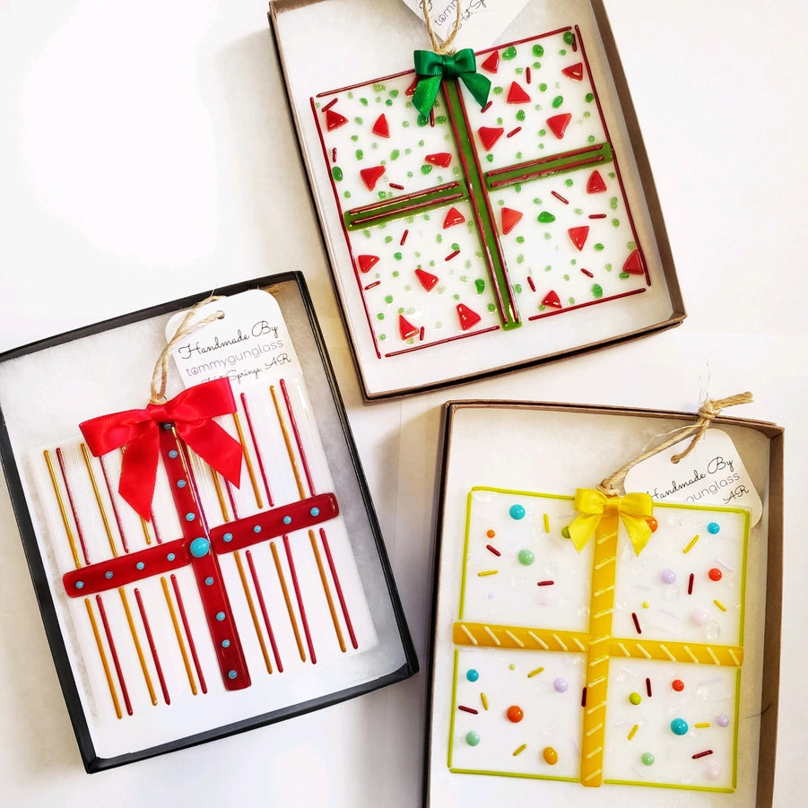 Three gift box shaped ornaments with decorative ribbons and patterns on a white background