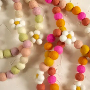 Colorful felt ball garland on a textured surface
