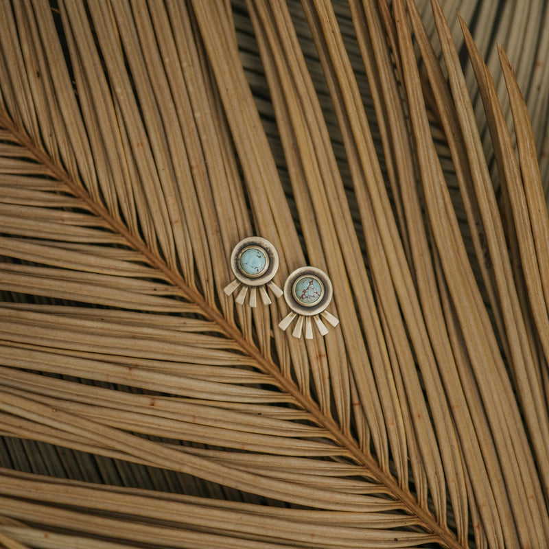Pair of earrings on a dried palm leaf