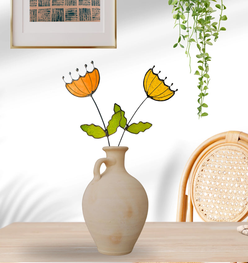 Decorative vase with stylized flowers on a wooden surface, with a chair and wall art in the background.