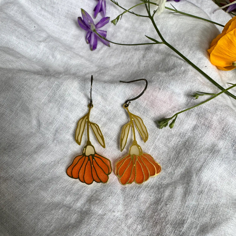 Floral earrings on a white fabric background with flowers around