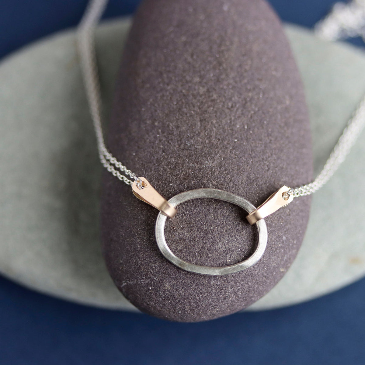 Silver necklace with a circular pendant on a gray stone