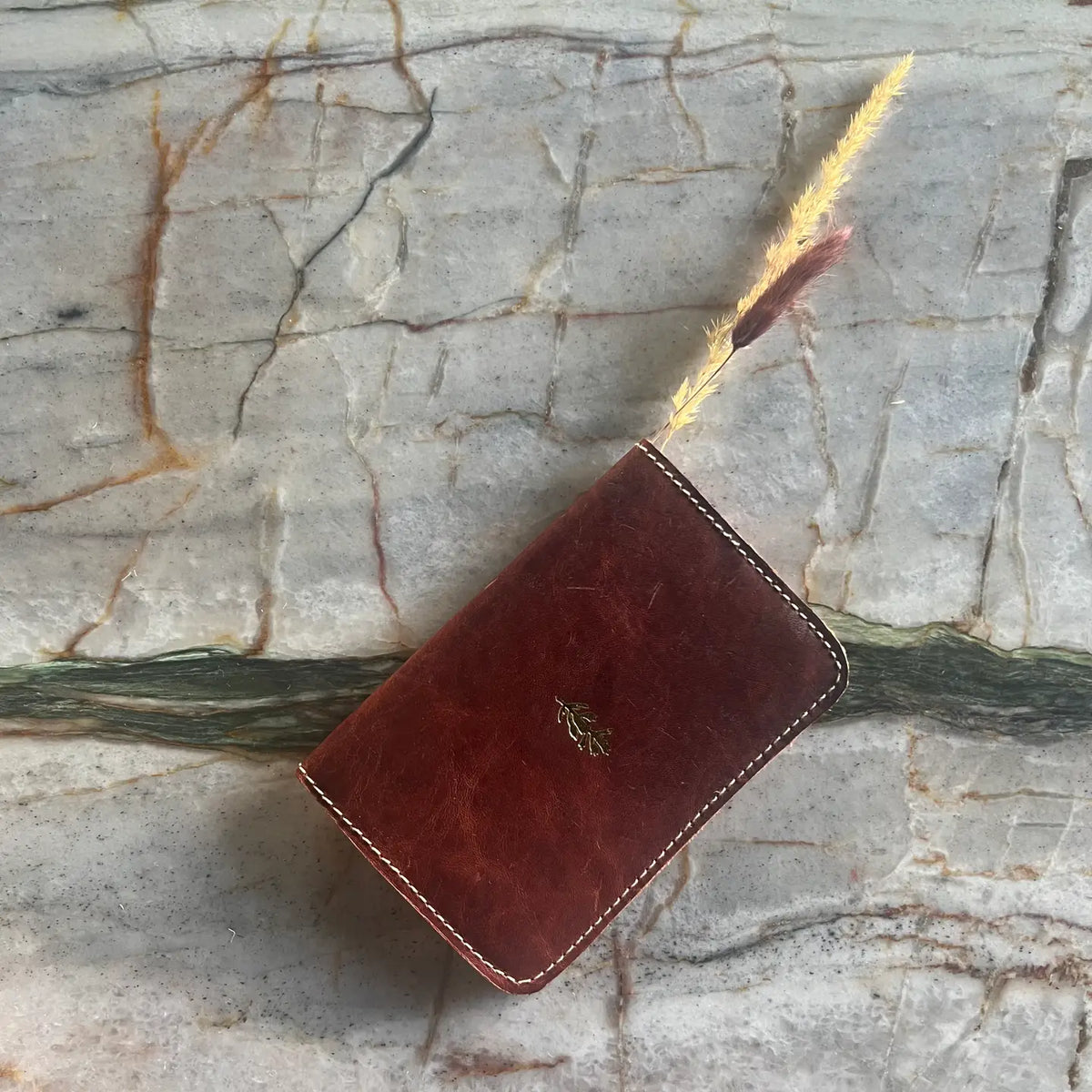 Brown leather wallet with a gold emblem on a marble surface