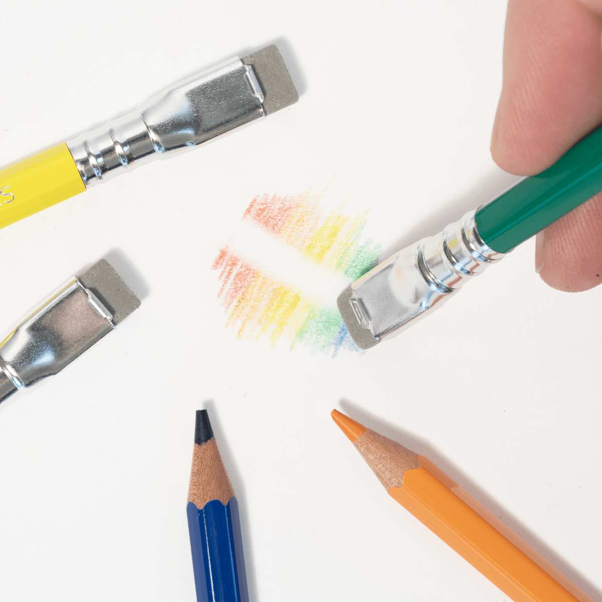 Colorful pencils and erasers with color swatches on a white background with a section having been erased