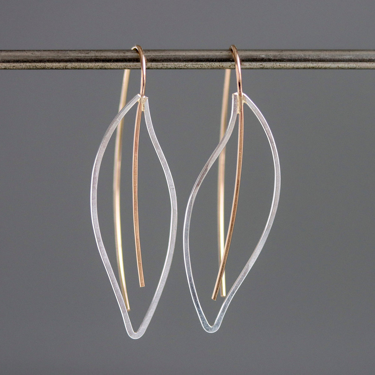 Pair of gold and clear leaf-shaped earrings on a gray background