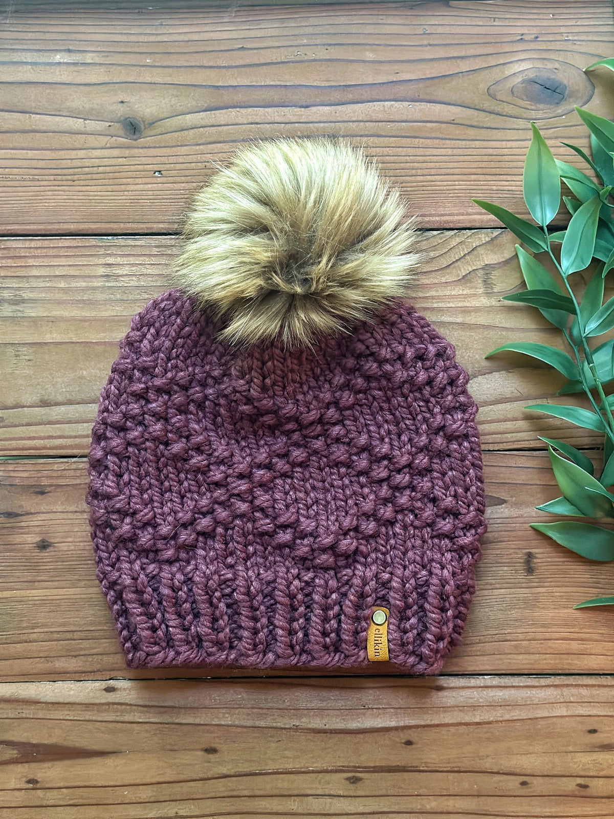 Knitted beanie with a pom-pom on a wooden surface