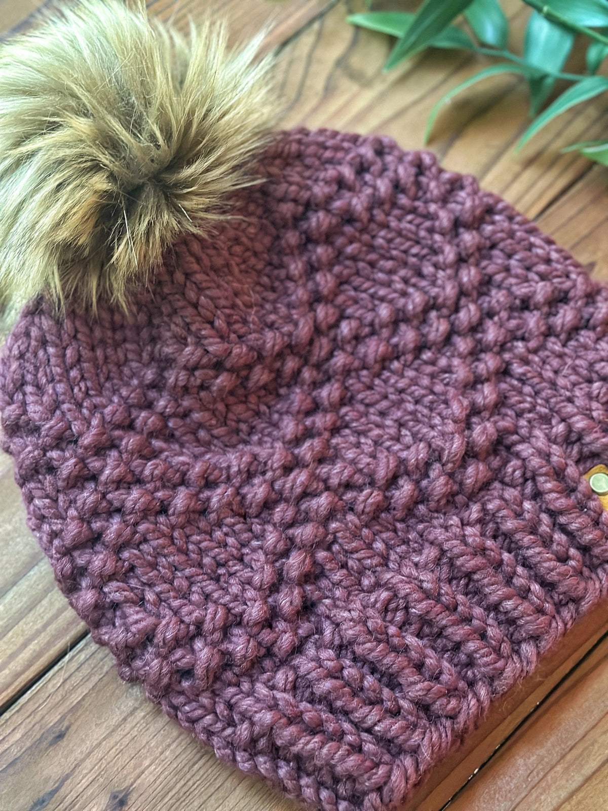 Knitted beanie with a pom-pom on a wooden surface