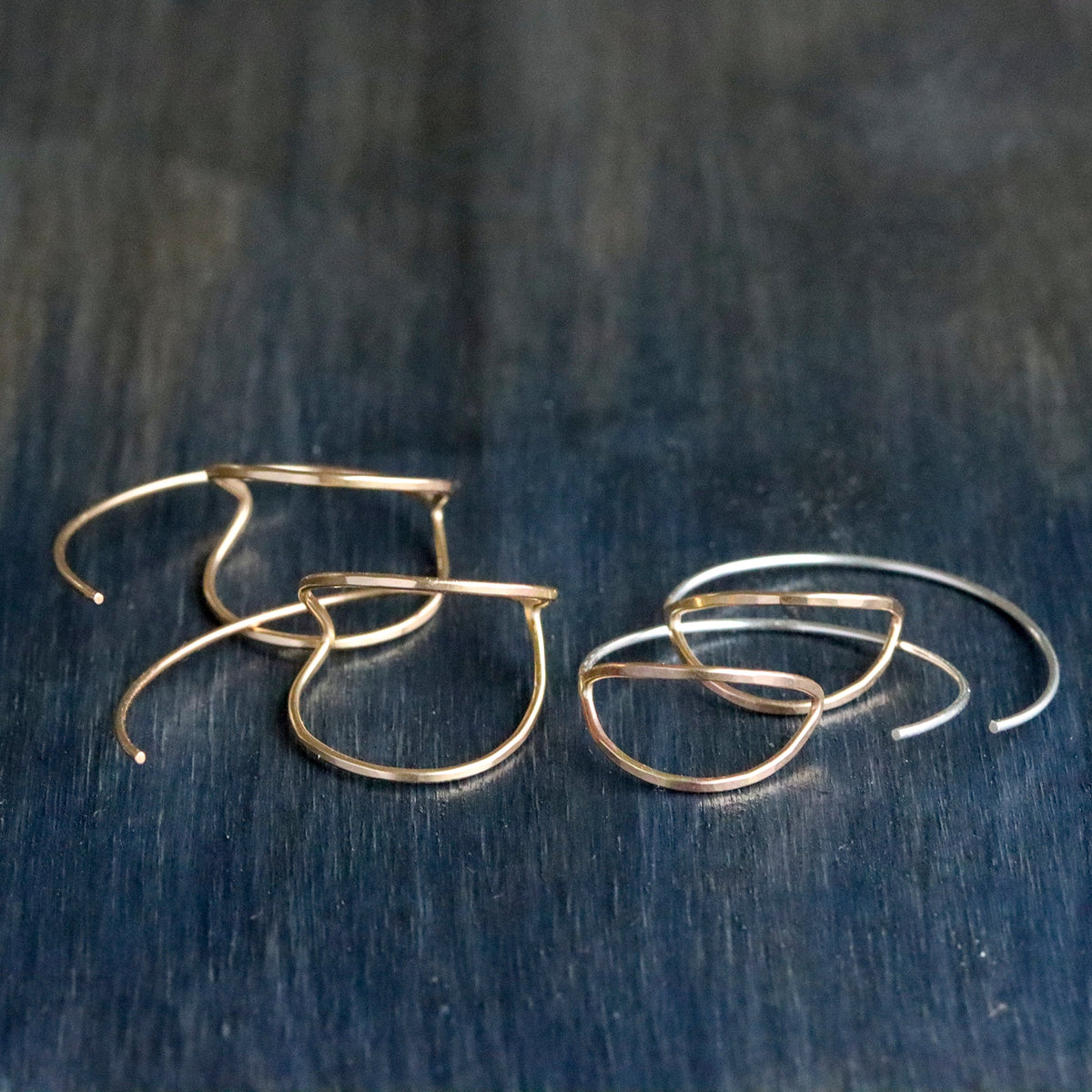 Gold hoop earrings on a dark wooden surface