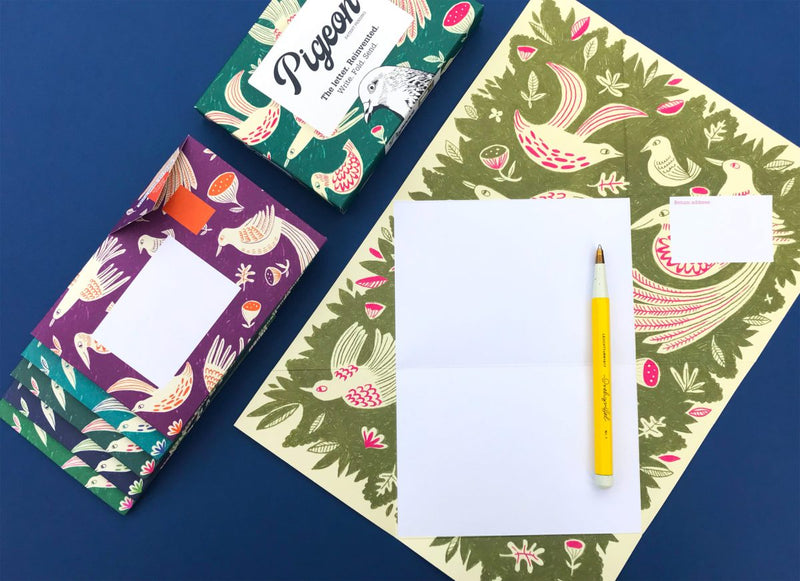 Colorful stationery set with patterned envelopes and a pen on a blue background