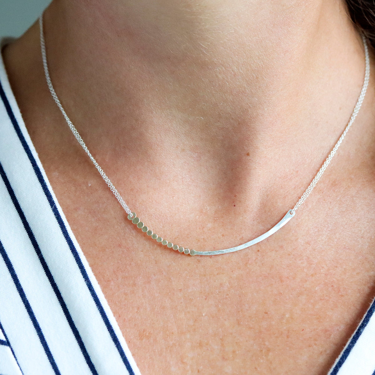 Silver necklace on a person's neck with a blurred background