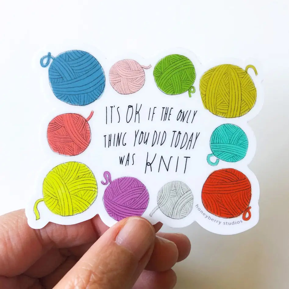 Colorful yarn ball stickers with a motivational quote held by a hand.