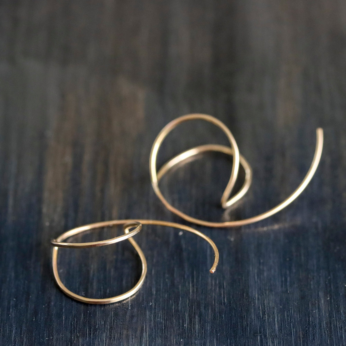 Gold hoop earrings on a dark wooden surface