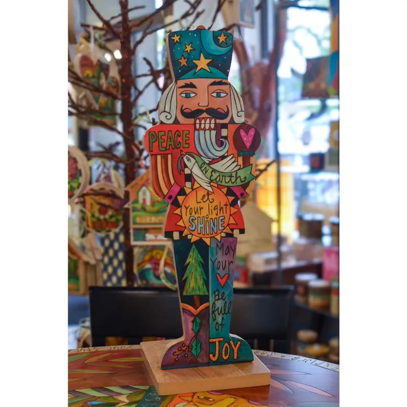 Colorful wooden Nutcracker figure with motivational phrases on a table.