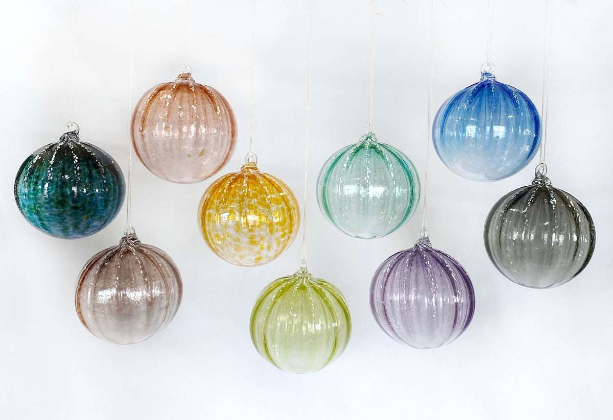 Colorful glass ornaments hanging against a white background