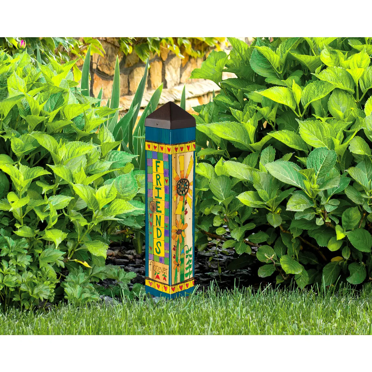 Decorative garden post with 'Friends' text and floral design in a garden setting