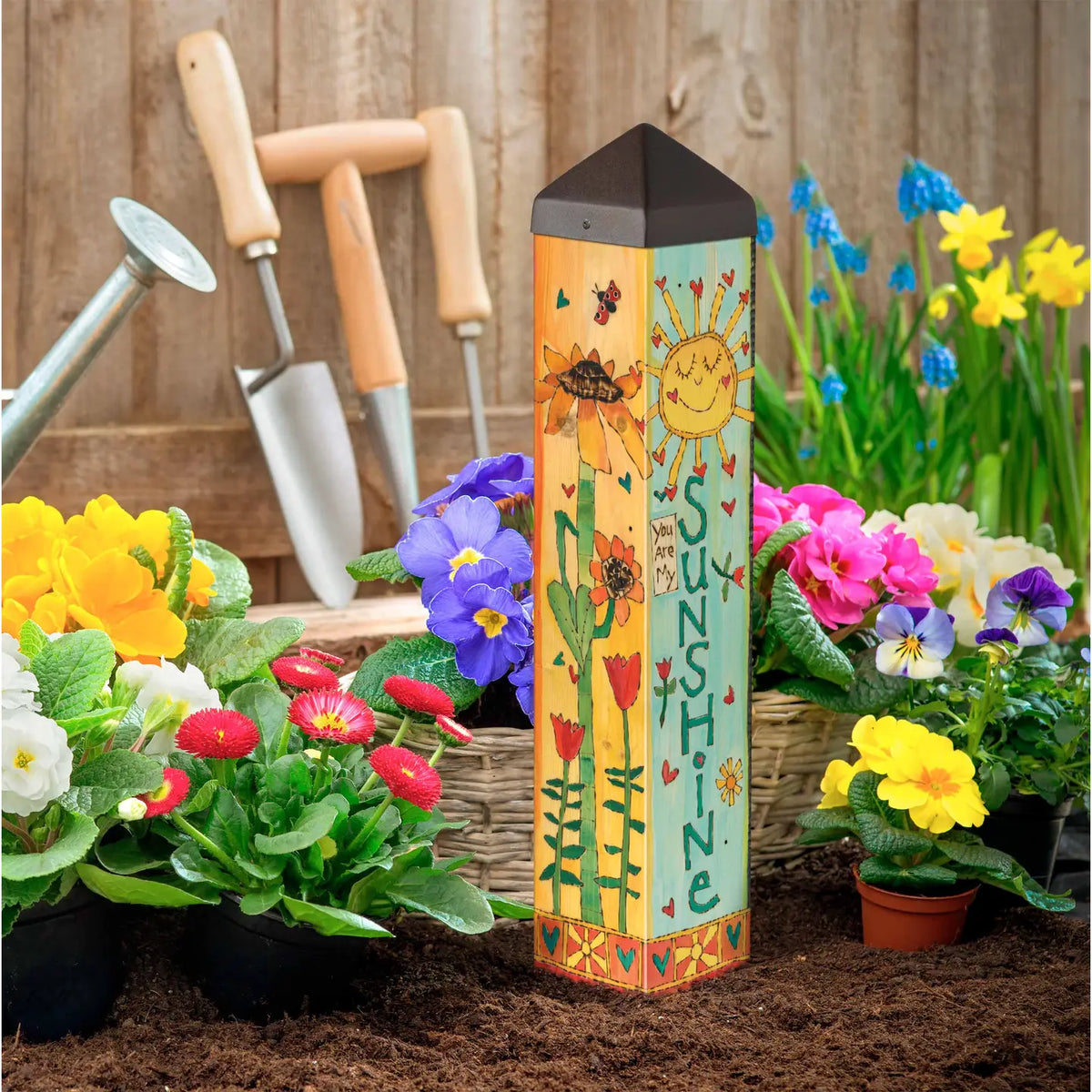 Decorative garden post with sun and flower design in a garden setting