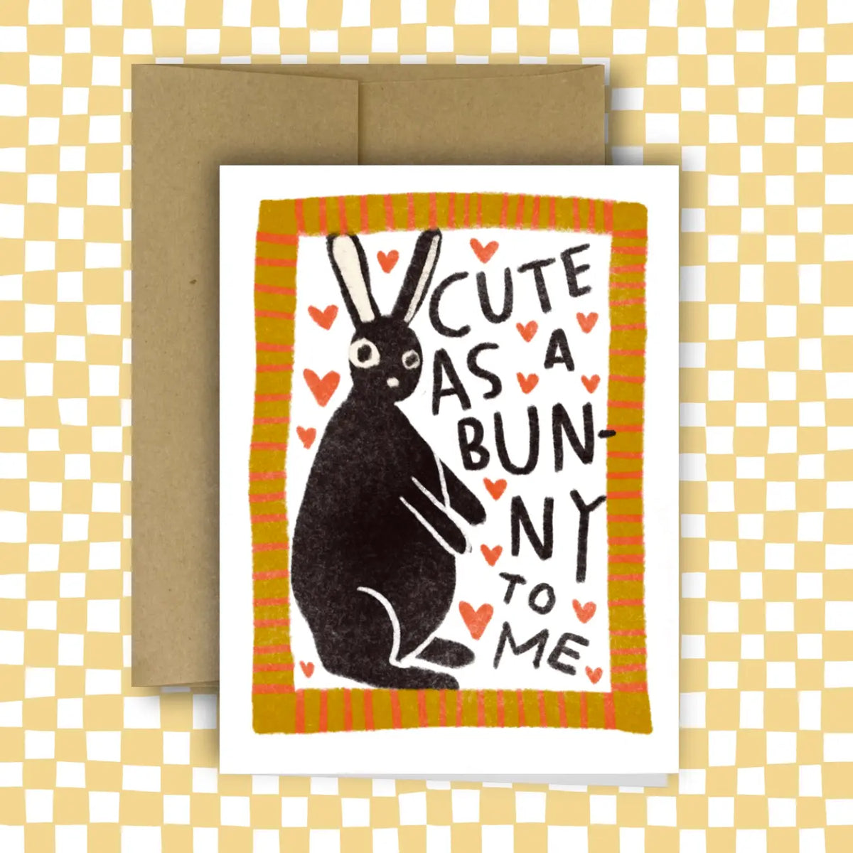 Greeting card with a black rabbit illustration and text 'Cute as a bunny to me' on a checkered background.
