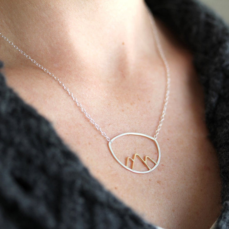 Necklace with a mountain pendant worn by a person