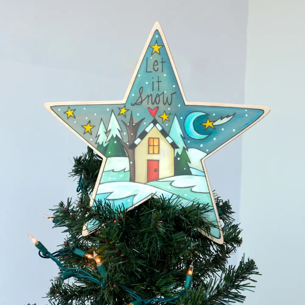 Decorative star ornament with a winter scene and 'Let it Snow' text on a Christmas tree.