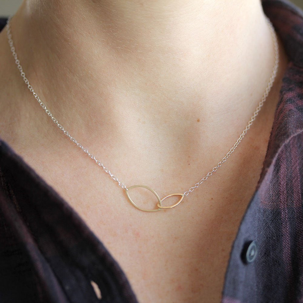 Necklace with a gold and silver infinity symbol on a person's neck