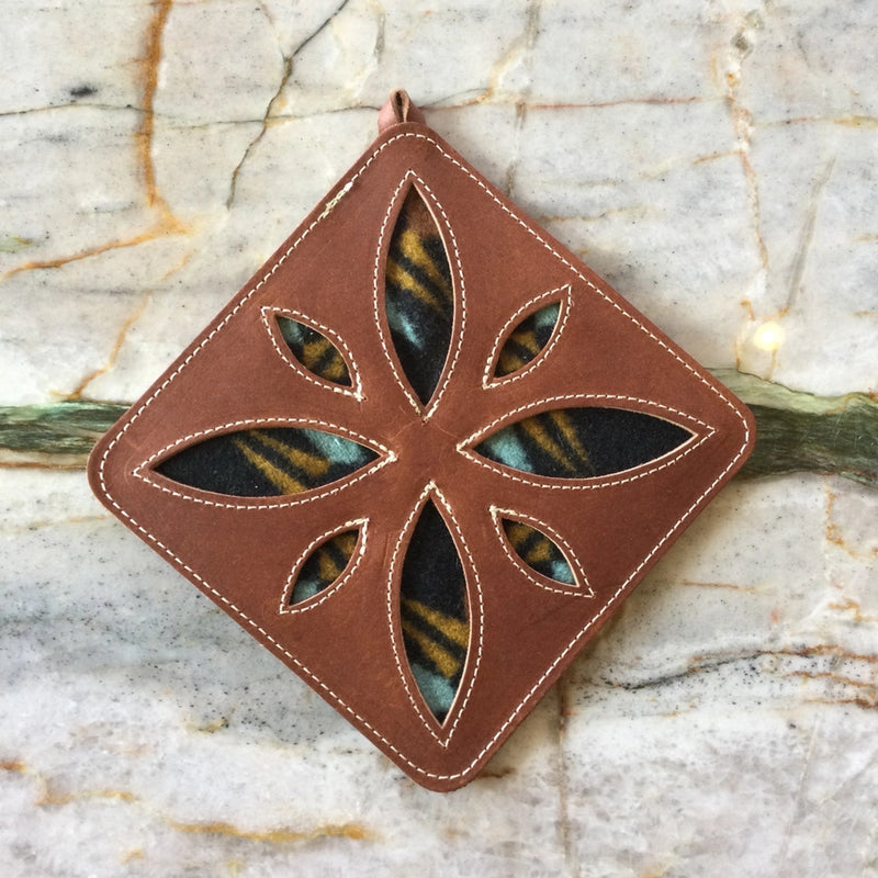 A square-shaped leather trivet with a woolen edge design, featuring brown leather and a patterned woolen border.