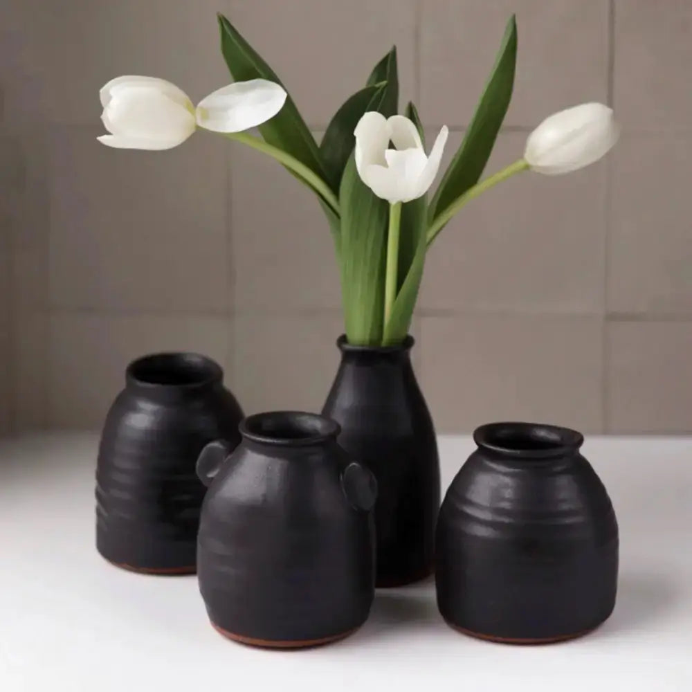 Set of black ceramic vases with white tulips on a neutral background