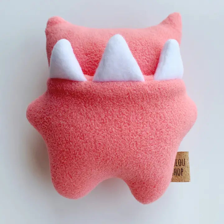 Pink plush toy with white teeth on a light gray background