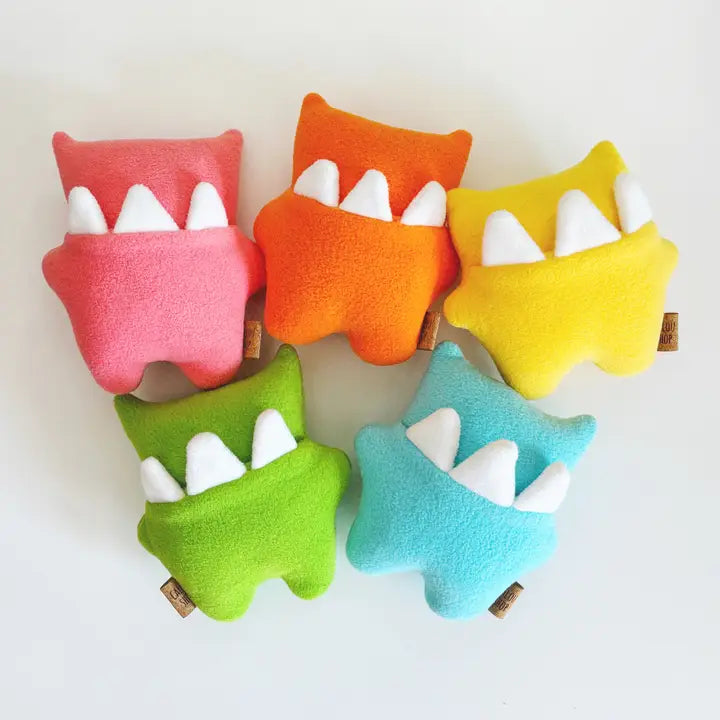 Colorful plush toys shaped like monsters with white teeth on a white background