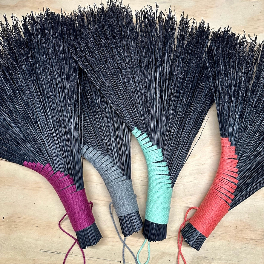 Four brooms with colorful handles on a wooden surface