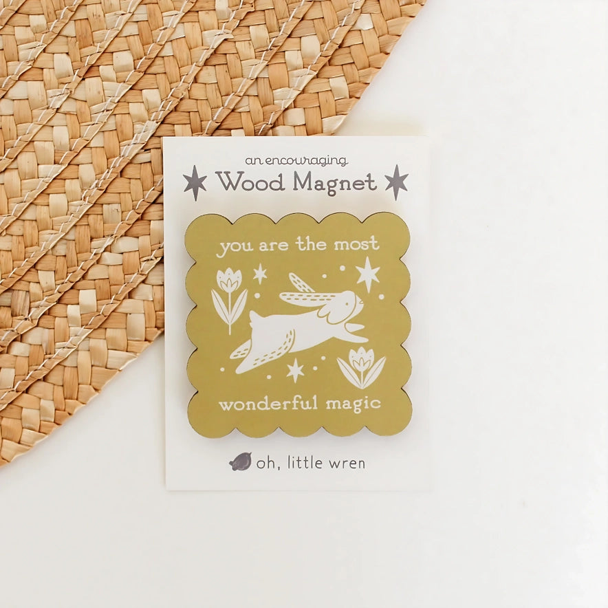 Wood magnet with rabbit illustration and text on a woven surface
