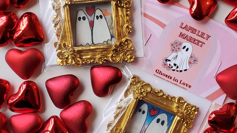 Decorative items with gold frames, red hearts, and a card featuring ghosts in love on a white background.