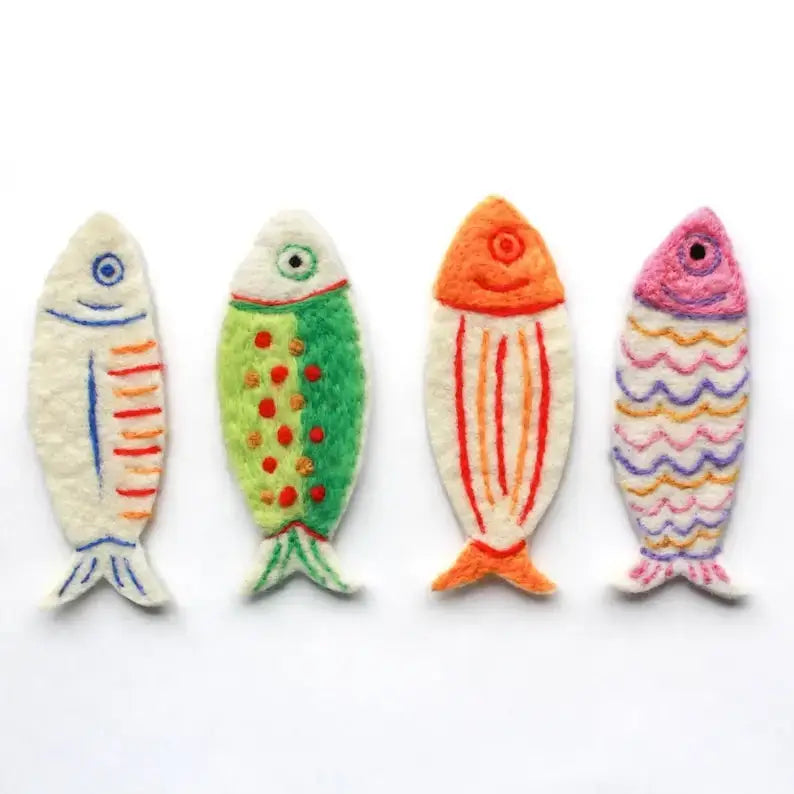 Four handcrafted felt fish ornaments in various colors and patterns, arranged in a row on a plain white background.