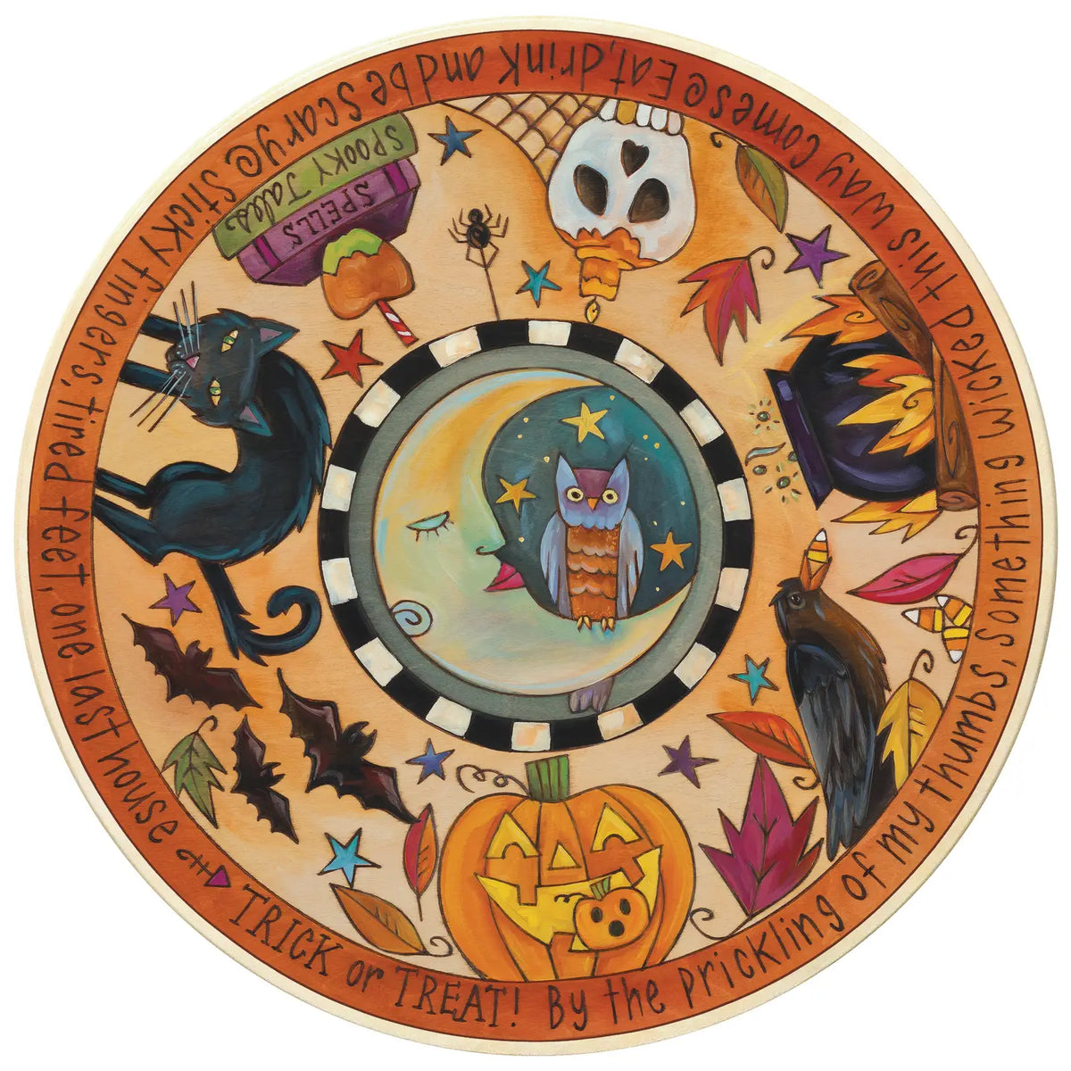 A circular Halloween-themed decorative lazy susan with a whimsical painted design. The center features an owl under stars inside a black-and-white checkered ring, surrounded by a warm orange border with illustrations of a black cat, a jack-o'-lantern, a raven, autumn leaves, stars, and handwritten text around the edge.