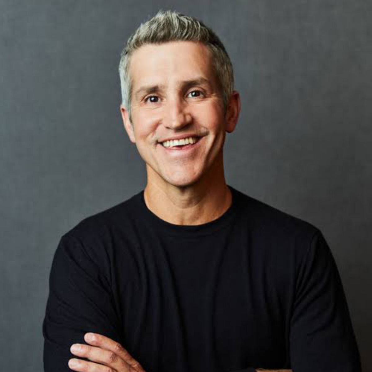 Author Jon Acuff wearing a black shirt against a dark background