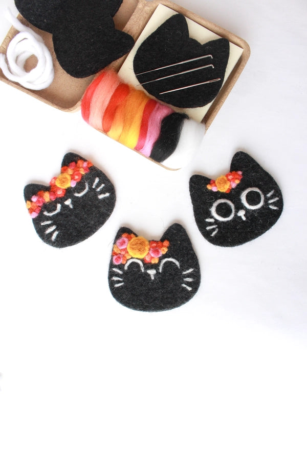 Black felt cat heads with floral designs on a white background