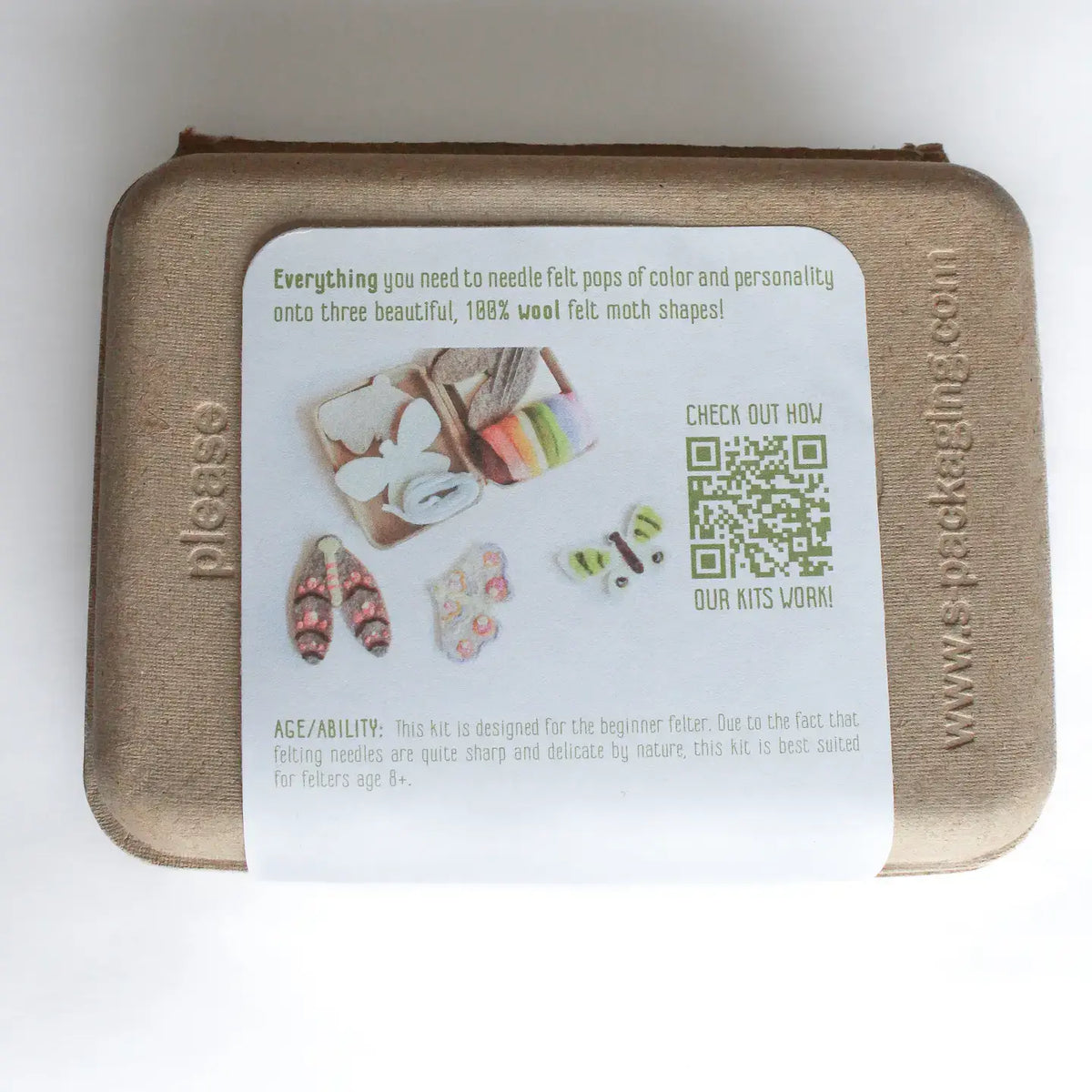 A square kraft-paper style felt kit box with a large white instruction card on the front, photographed from above on a white background. The card includes product description text, small photos of felt items, a QR code, and the website www.