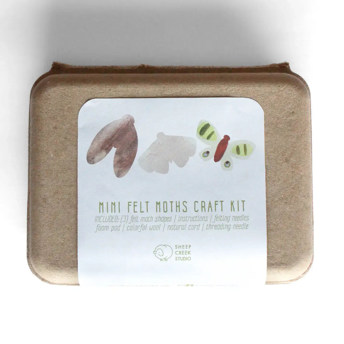 A mini felt noths craft kit in a square kraft paper box with a white paper label. The label features watercolor illustrations of felt shapes and a butterfly, with the text 'MINI FELT NOTHS CRAFT KIT' and 'SHEEP CREEK STUDIO' at the bottom.