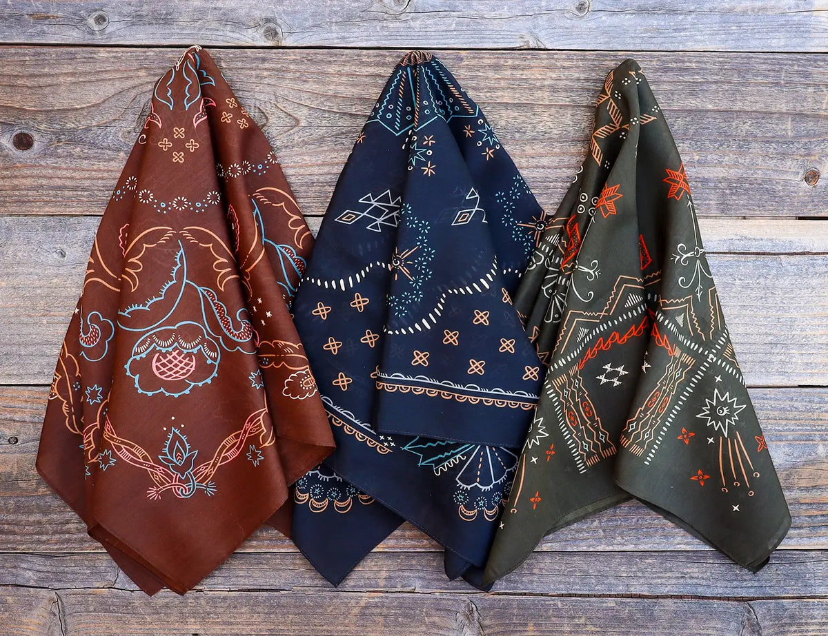 Three patterned scarves in brown, blue, and green on a wooden surface