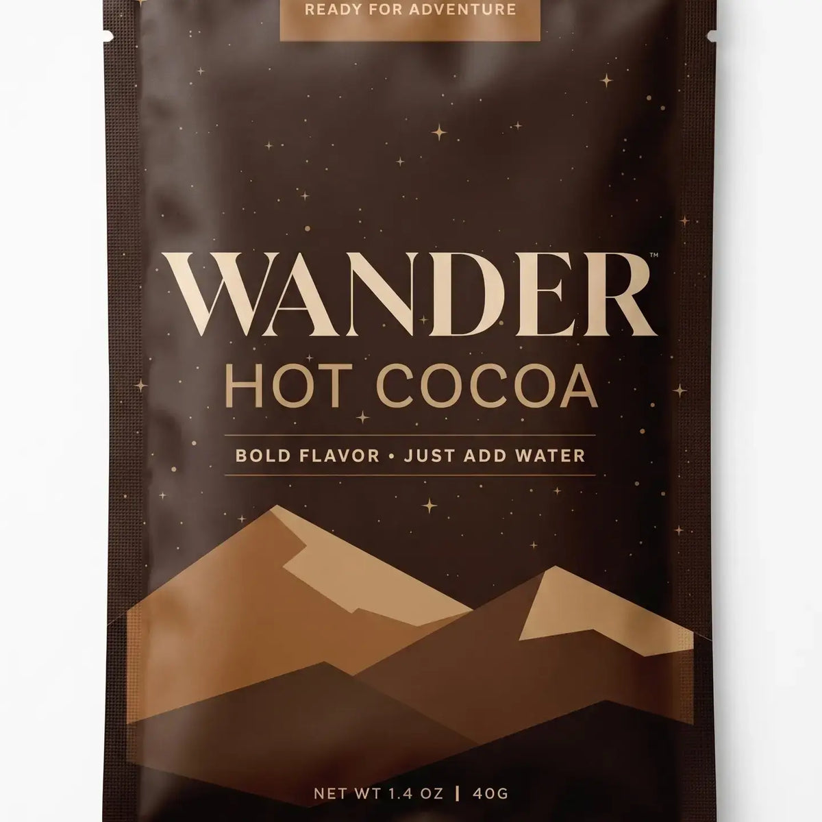 A single stand-up pouch of Wander Hot Cocoa on a plain white background. The package is dark brown with gold and beige typography and mountain graphics near the bottom.