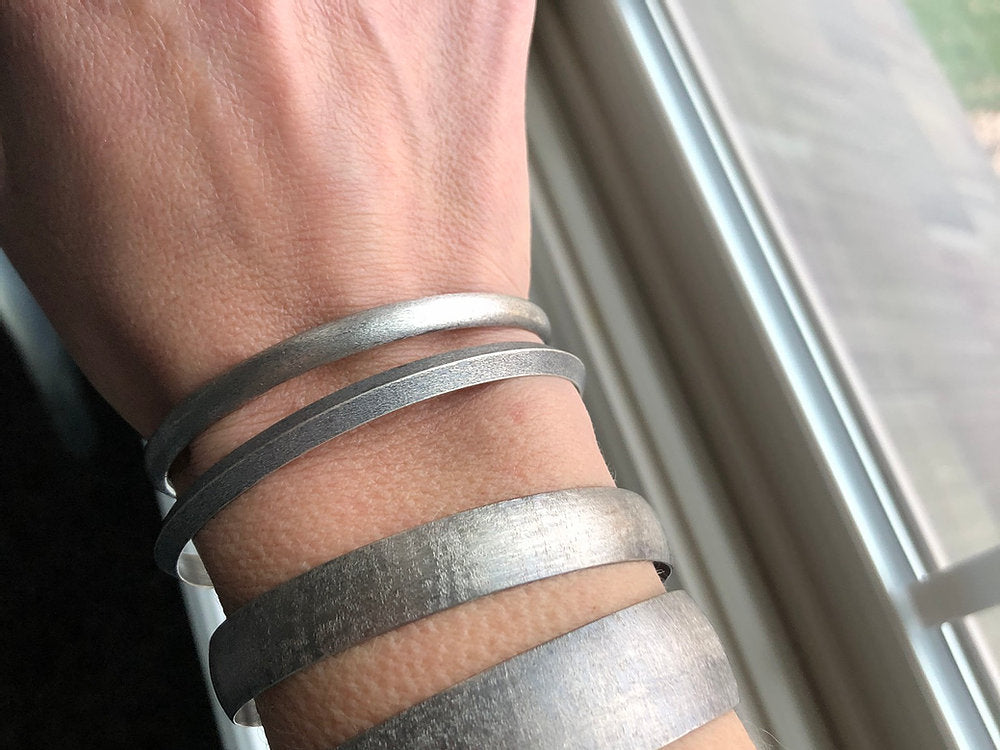 Stack of Oxidized Cuff Bangle Bracelets displayed on a white woman's wrist