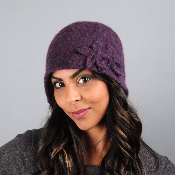 Model of a handmade purple wool hat with two wool flowers sewn on. Handmade by Julie Sinden Handmade.