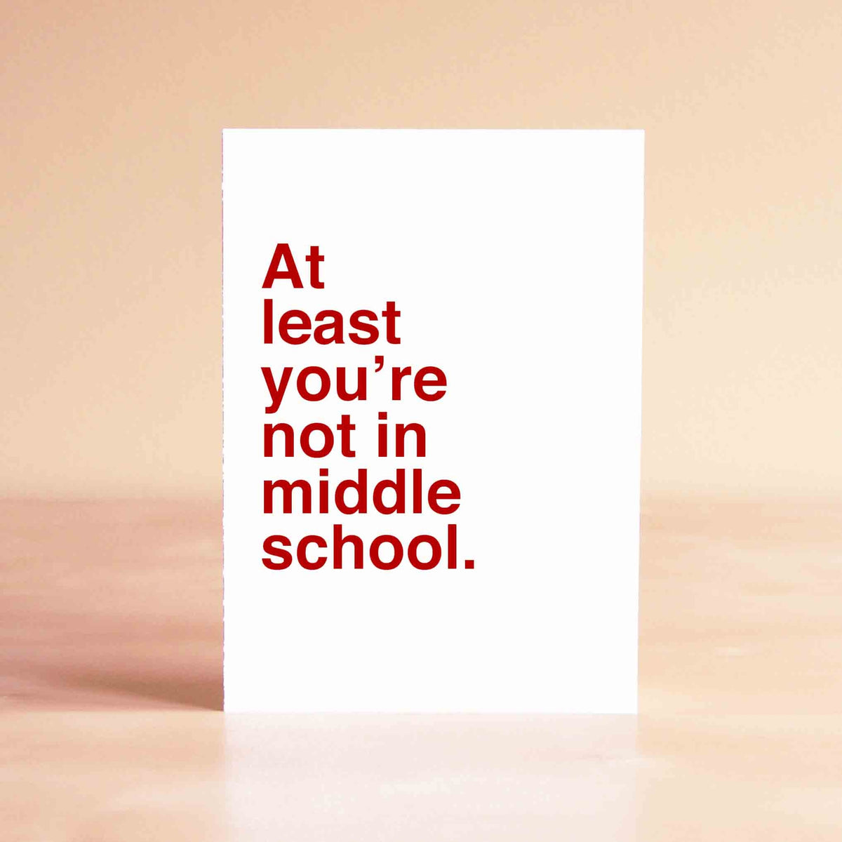 White card with red lettering reading "At least you're not in middle school."