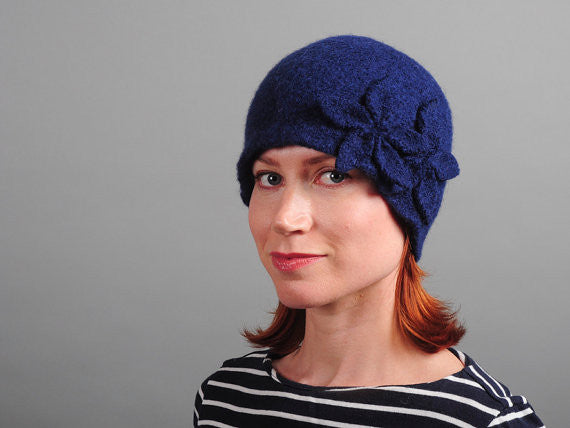 Model of a handmade navy blue wool hat with two wool flowers sewn on. Handmade by Julie Sinden Handmade.